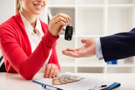 Image of a female loan specialist handing car keys to an outstretched hand.