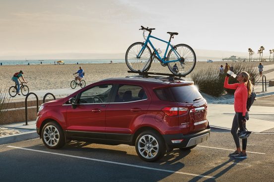 Image of a red 2019 Ford EcoSport at the beach with a bike hitched on top.