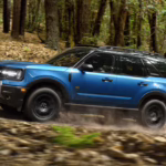 2026 Ford Bronco Sport driving through a forest on a trail.